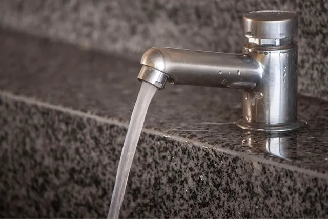 Agua saliendo de un grifo sobre una encimera de granito